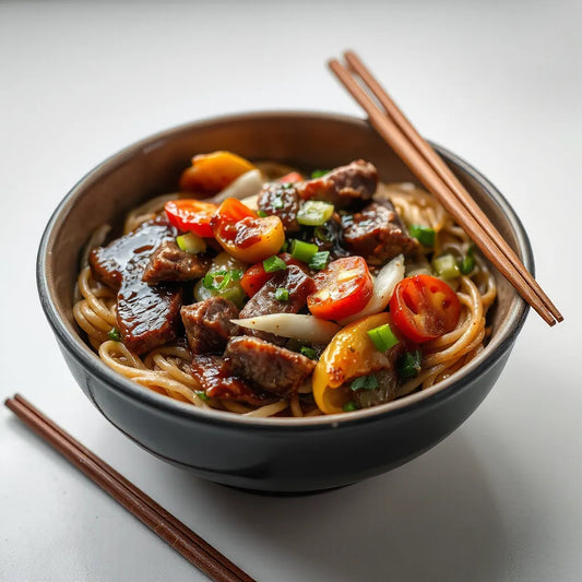Glossy Korean BBQ stir fry noodles topped with beef, vegetables, and scallions in a bowl