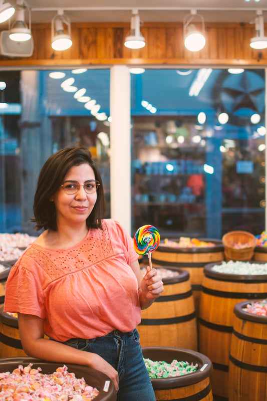 woman in orange crew neck shirt holding lollipop