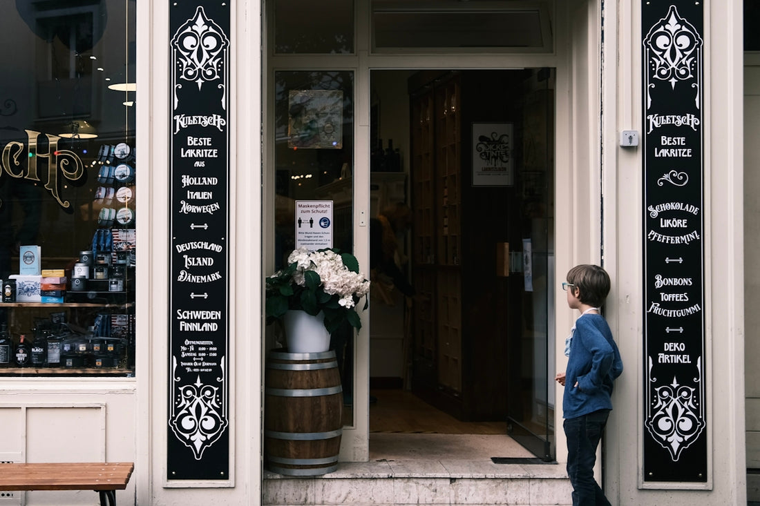 A young boy stands outside a shop entrance.
