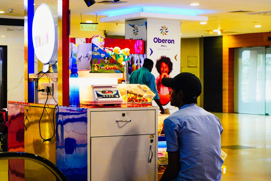A young man at a colorful kiosk in a mall.