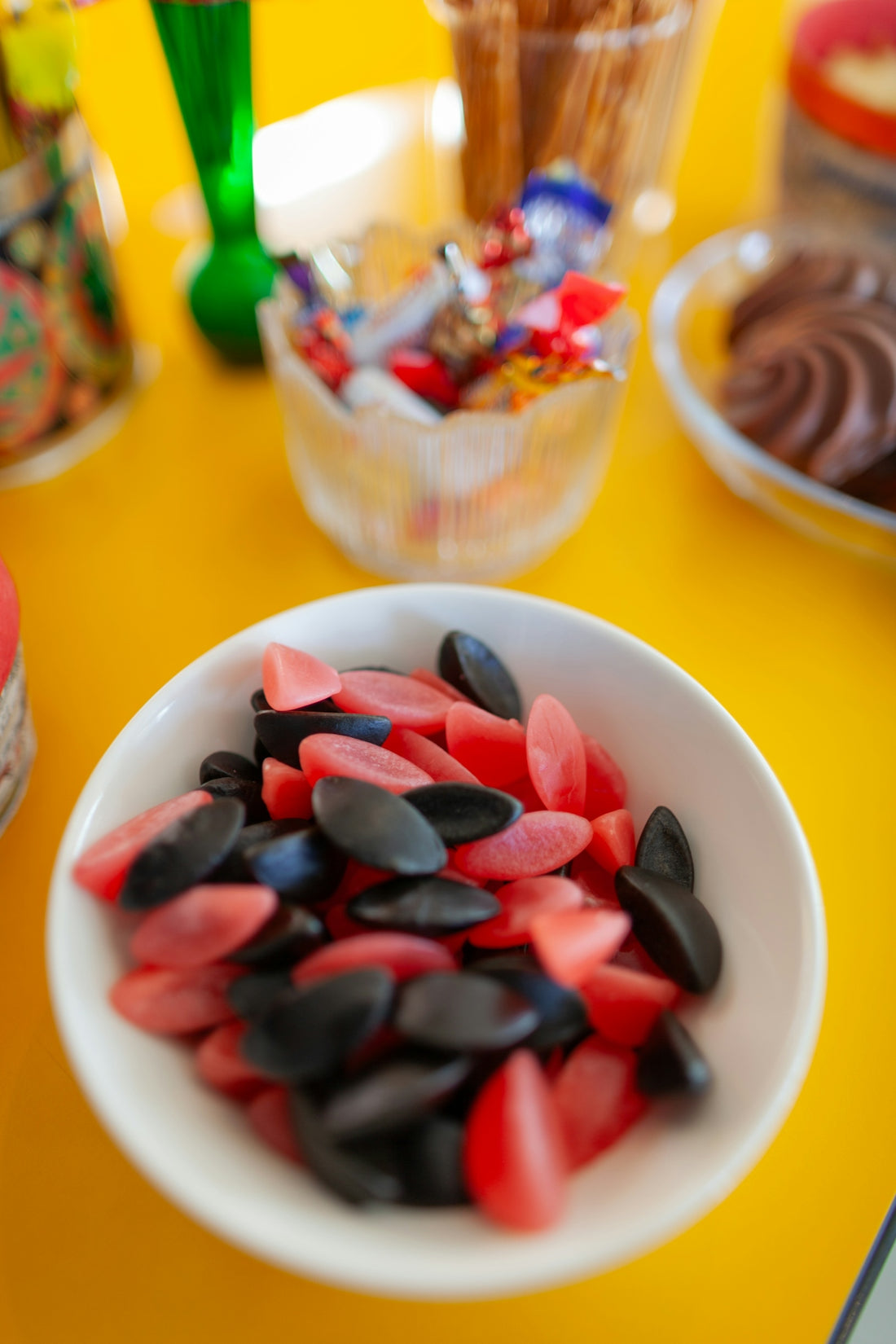 Red and black licorice candies in a white bowl.