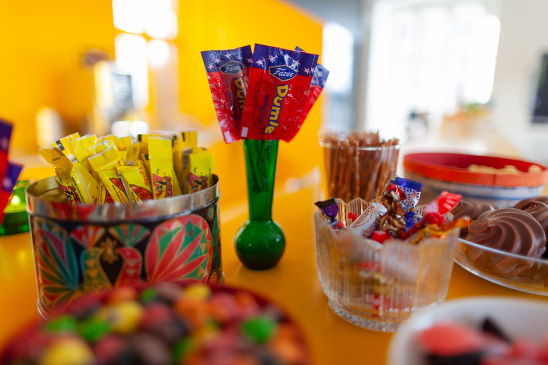 Colorful candies and snacks arranged on a vibrant yellow table.