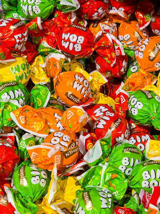 A pile of colorful wrapped candies in red, orange, yellow, and green foil
